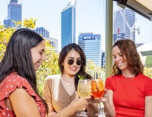 Colleagues enjoying drinks at a corporate Christmas party in Perth, with city skyline views at The Island at Elizabeth Quay