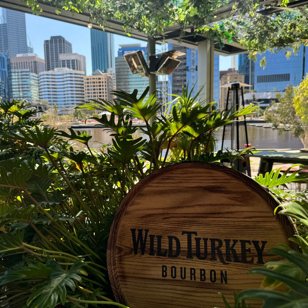 Wild Turkey bourbon wooden sign at the Island at Elizabeth Quay Restaurant, with Perth skyline in the background